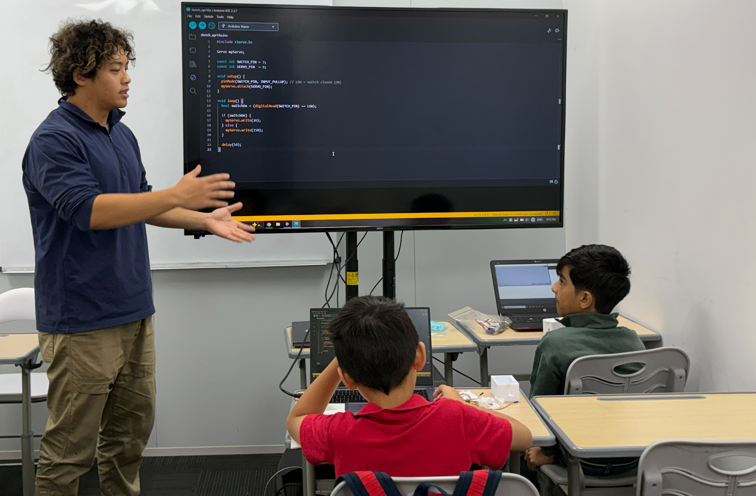 Instructor teaching Arduino code to students in a classroom